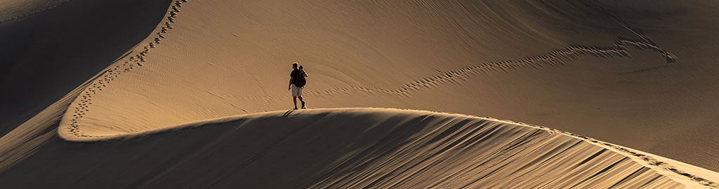 Man walking across dunes in Death Valley 
