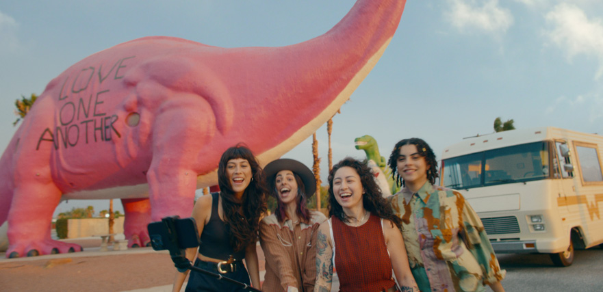 Four young road trippers in front of a pink dinosaur and car in the Playful Journeys spot by Visit California